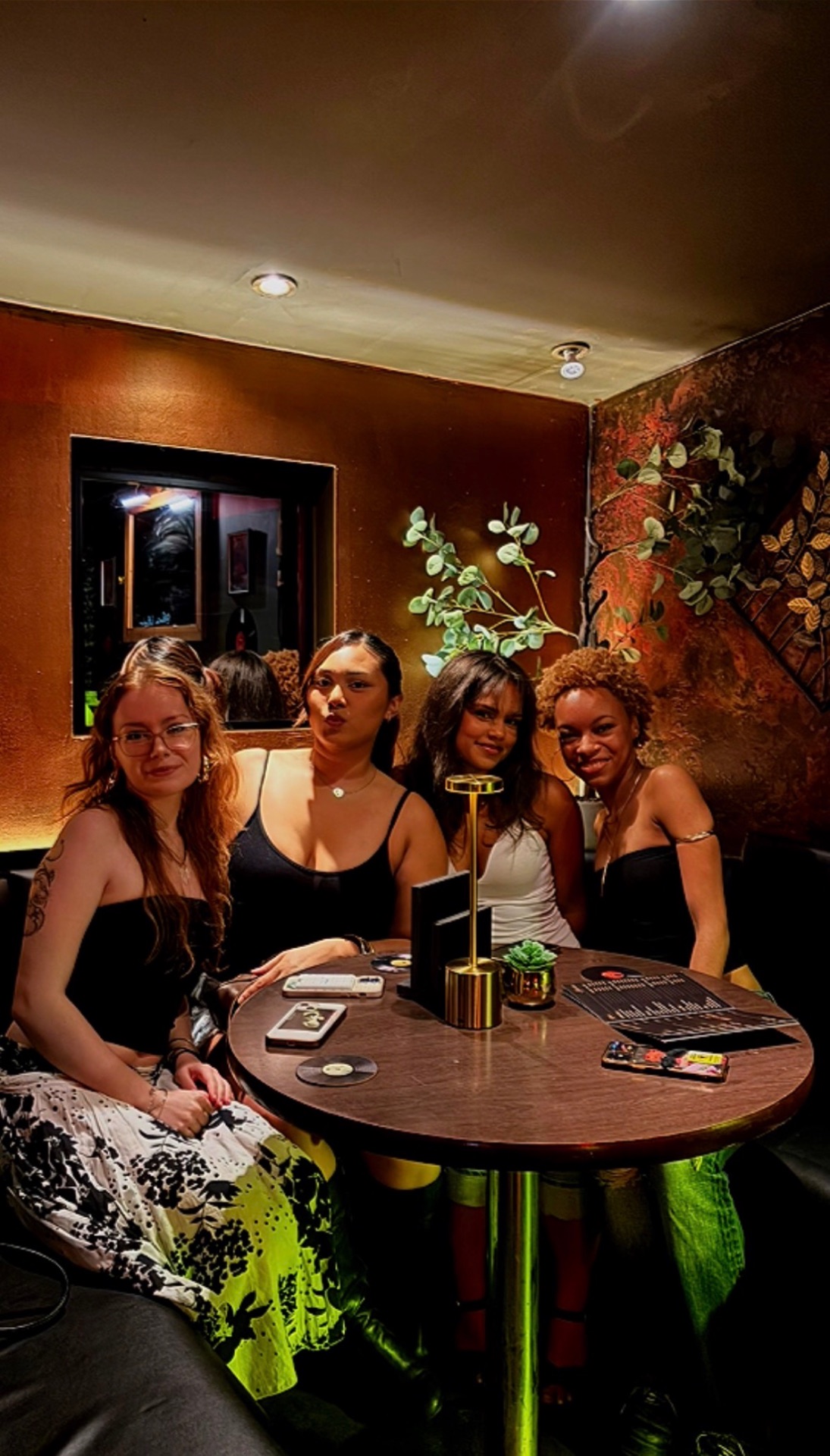 Friends around a round table in the Ronin Room, under warm lantern light